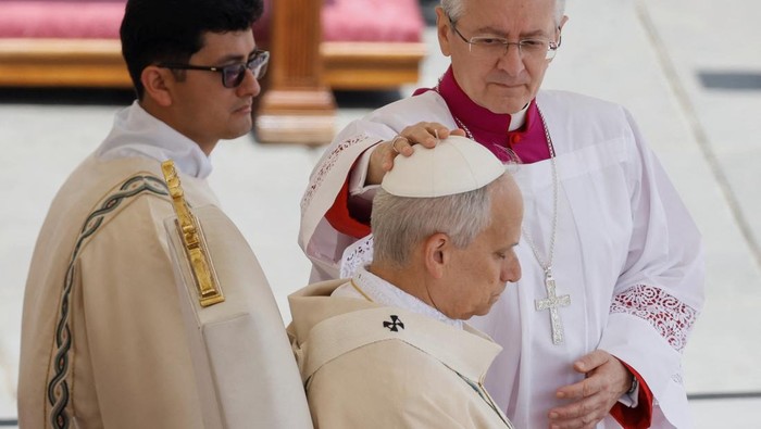 A member of the clergy adjusts Pope Leo XIV's zucchetto during his inaugural Mass in Saint Peter’s Square, at the Vatican, May 18, 2025.  REUTERS/REMO CASILLI
