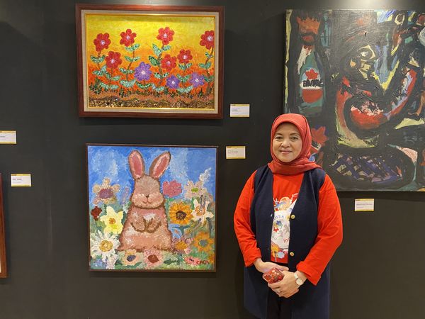 Ketua Komunitas Pesona Autistik Indonesia (PAI), Mirah Hartika, bersama lukisan anaknya, yang juga penyandang autis