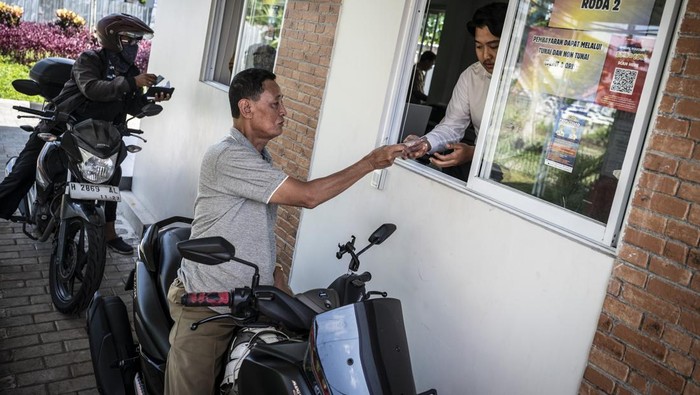 Petugas (kanan) melayani pengendara sepeda motor membayar pajak kendaraan bermotor di Layanan Drive Thru Pajak Daerah Kota Semarang, Jawa Tengah, Senin (19/5/2025). Kementerian Keuangan melaporkan realisasi penerimaan pajak hingga triwulan I 2025 mencapai Rp322,6 triliun, atau sekitar 14,7 persen dari target pajak 2025 sebesar Rp2.433,5 triliun. ANTARA FOTO/Aprillio Akbar