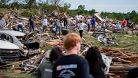 Orang-orang menyaksikan para relawan membersihkan puing-puing di lingkungan Sunshine Hills setelah serangkaian tornado menghantam Laurel County, di London, Kentucky, AS, Minggu (18/5/2025).