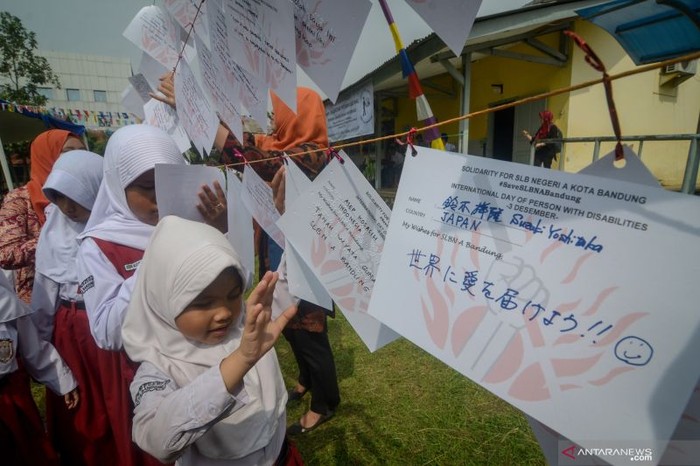 Sejumlah siswa disabilitas membaca huruf braile di kertas yang bertuliskan dukungan kepada SLBN A Kota Bandung saat aksi solidaritasi di SLBN A, Bandung, Jawa Barat, Jumat (6/12/2019). (ANTARA FOTO/RAISAN AL FARISI)