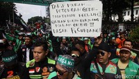 Para pengemudi membawa spanduk dan poster berisi aspirasi soal keadilan tarif dan perlindungan hukum.  