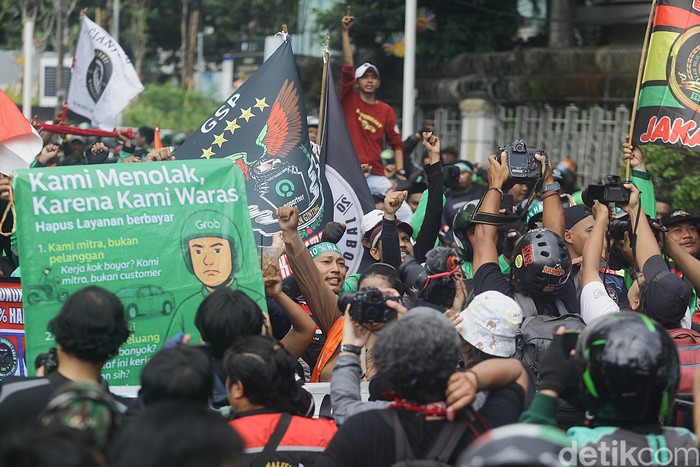 Ratusan ojol demo di Patung Kuda tuntut komisi 10% dan desak pemerintah sahkan UU Transportasi Online. Jalan Medan Merdeka pun dikuasai para ojol.