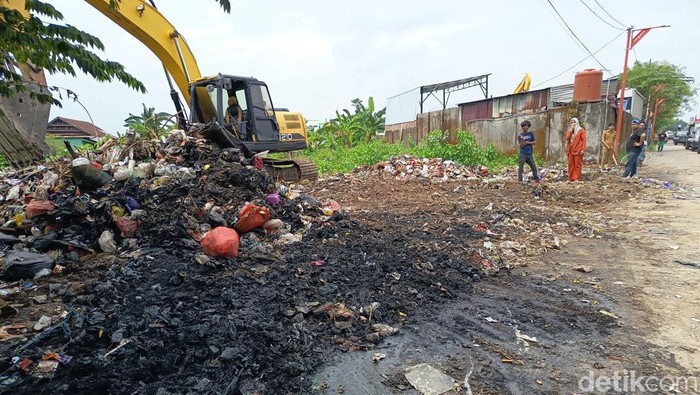 Ekskavator dikerahkan membersihkan tumpukan sampah yang menjadi pemicu kecelakaan pikap di Makassar.