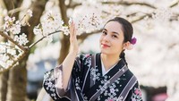 Senyum manisnya berfoto memakai kimono dengan latar bunga Sakura yang mekar. 