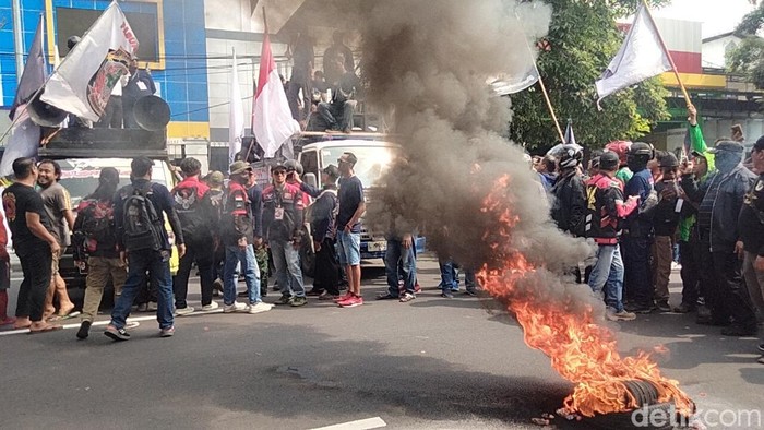 Massa demo ojol bakar ban bekas di depan kantor Diskominfo Jatim.