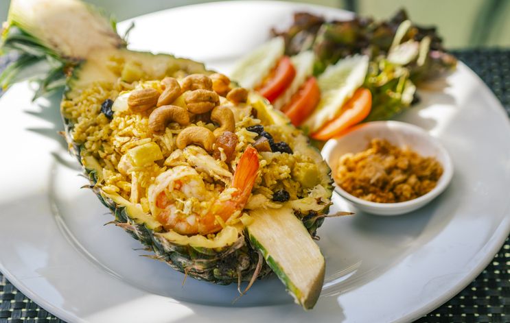 Pineapple fried rice with shrimps, Thai food popular menu of fried rice, beautiful food decoration, serve fried rice in half fresh pineapple, cashew nuts on top. Close up food image, natural lighting.