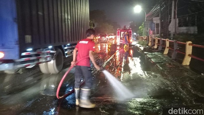 Petugas membersihkan sisa lumpur setelah banjir surut di Jalur Pantura Pasuruan.