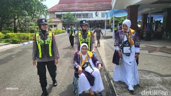 Polwan Polres Bojonegoro membantu jemaah calon haji saat hendak diberangkatkan ke Asrama Haji Surabaya.