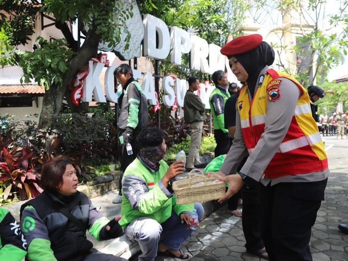 Polwan Polresta Solo membagikan snack dan air mineral kepada massa demo Garda Ojol Solo Raya, Selasa (20/5/2025).