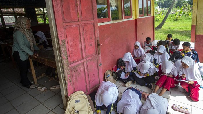 Potret Siswa Belajar di Teras gegara Sekolah Kurang Ruang Kelas Sejumlah murid mengikuti kegiatan belajar mengajar di teras ruang kelas SD Negeri Bojen 2, Sobang, Pandeglang, Banten, Selasa (20/5/2025). Pihak sekolah mengatakan, selama tiga tahun terakhir murid kelas tiga A dan B terpaksa mengikuti kegiatan belajar di teras sekolah secara bergantian setiap minggunya, sementara untuk murid kelas satu dan dua diterapkan sistem masuk bergantian pada pagi dan siang karena kekurangan ruang kelas. ANTARA FOTO/Angga Budhiyanto/foc.