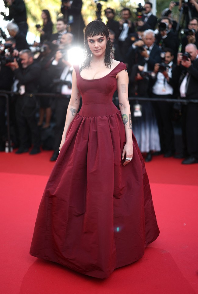 Dengan percaya diri, ia berjalan di karpet merah mengenakan gaun merah marun dengan rok lebar. Foto: REUTERS/Stephane Mahe