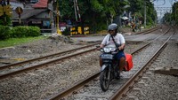Seorang pengendara sepeda motor tertangkap kamera saat melintasi jalur kereta di Jalan Pramuka, Jakarta, Rabu (21/5/2025). Aksi nekat ini dilakukan tanpa memperhatikan potensi bahaya dari kedatangan kereta yang sewaktu-waktu bisa melintas.