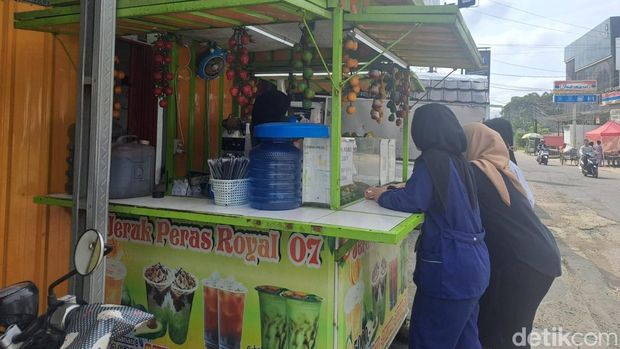 Tiga remaja membeli es teh jumbo dengan menggunakan QRIS.
