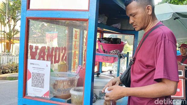 Ujang, salah satu pedagang kaki lima di Palembang yang menggunakan QRIS untuk usahanya.