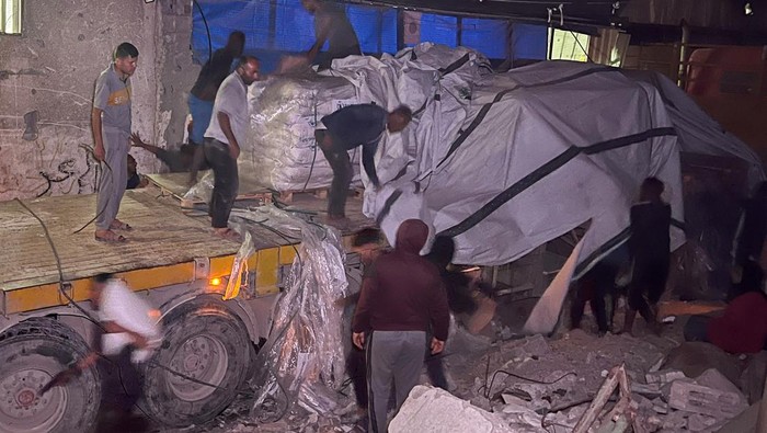 Palestinian workers unload sacks of flour from an aid truck at a bakery, in Khan Younis, southern Gaza Strip, May 21, 2025. REUTERS/Hussam Al-Masri