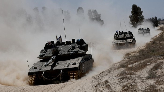 Military vehicles drive their way from the Israeli side of the Israel-Gaza border into Gaza, as seen from Israel, May 20, 2025. REUTERS/Amir Cohen     TPX IMAGES OF THE DAY