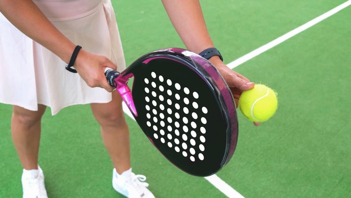 Close-up shot of unrecognizable woman ready to serve ball during padel tennis games on indoor court.