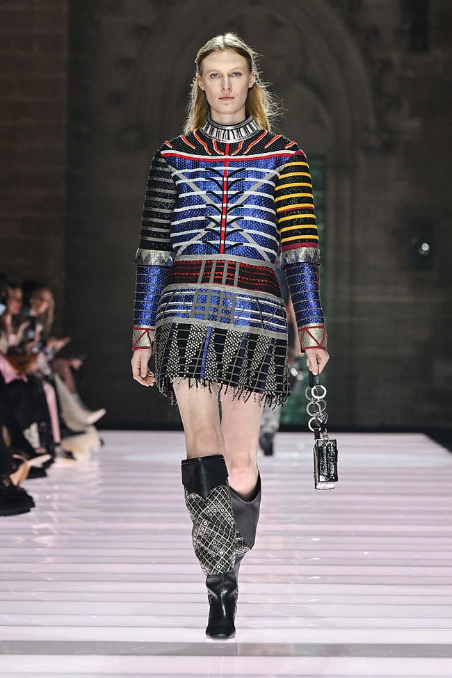 Dengan latar arsitektur Gotik yang megah, presentasi ini menampilkan busana yang terinspirasi dari era Arthurian hingga glam rock. Bayangkan Joan of Arc, tapi ia memakai kaus oversized baseball, seperti terusan, yang dilapisi metal keemasan. (Foto: Giovanni Giannoni/WWD via Getty Images)