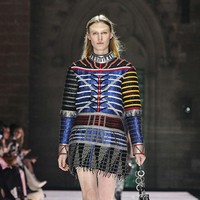 Dengan latar arsitektur Gotik yang megah, presentasi ini menampilkan busana yang terinspirasi dari era Arthurian hingga glam rock. Bayangkan Joan of Arc, tapi ia memakai kaus oversized baseball, seperti terusan, yang dilapisi metal keemasan. (Foto: Giovanni Giannoni/WWD via Getty Images)