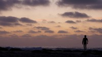 Langit temaram dan semilir angin laut menemani warga yang duduk santai menatap cakrawala di Pantai Cardiff.