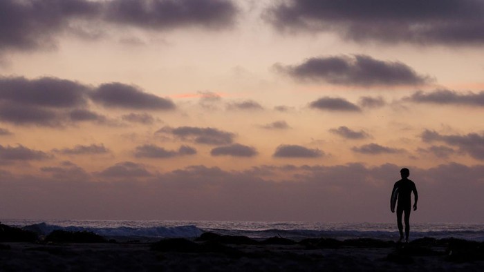 Di Cardiff Beach, langit senja menyapa pengunjung dengan warna jingga. Mereka menikmati momen damai di ujung hari.