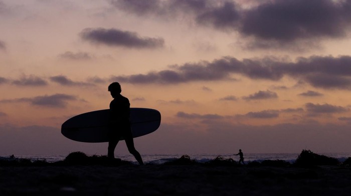 Menikmati Senja di Pantai Cardiff California Di Cardiff Beach, langit senja menyapa pengunjung dengan warna jingga. Mereka menikmati momen damai di ujung hari.