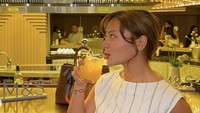 Amel Carla terlihat cantik mengenakan gaun putih saat menghadiri sebuah acara. Ia berpose di area bar sambil memegang segelas jus berwarna oranye. Foto: Instagram amelcarla