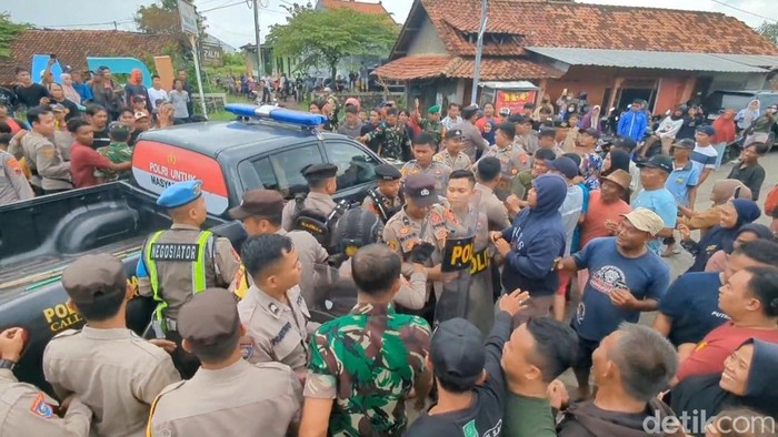 Polisi evakuasi Sekdes Sijambe, Wonokerto, Pekalongan, dari kerumunan massa, Jumat (23/5/2025). Peristiwa ini terkait aksi warga yang meminta sekdes mundur dari jabatannya.
