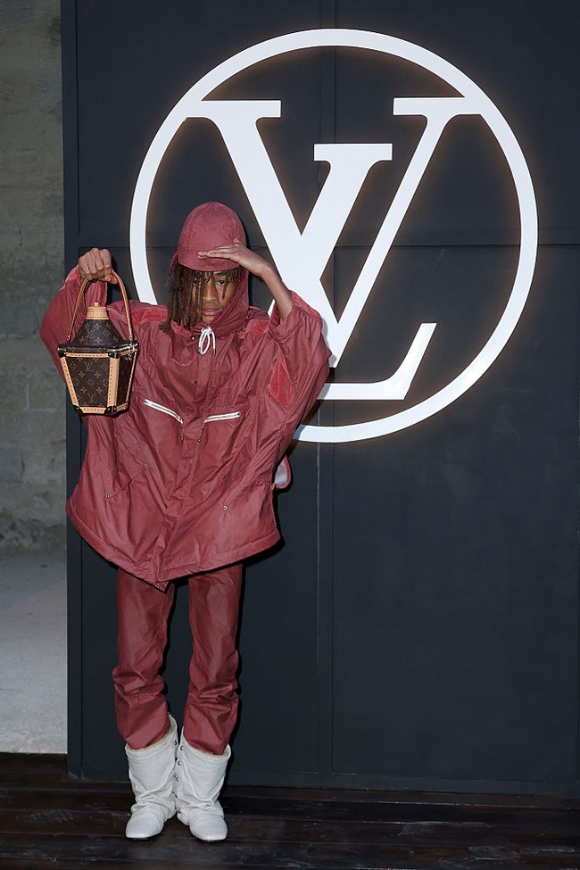 Sebagai pelengkap penampilan, Jaden membawa tas berbentuk lentera klasik bermotif monogram LV. Dia menentengnya sepeerti properti panggung, seolah ingin menunjukkan bahwa tas ini bukan sekadar aksesori fungsional, melainkan statement piece yang menambah lapisan cerita pada keseluruhan look-nya. Foto: Getty Images/Edward Berthelot