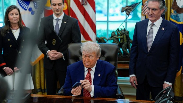 U.S. President Donald Trump holds an iPhone after it rang while he was speaking on the day he signs an executive order at the White House in Washington, D.C., U.S., May 23, 2025. REUTERS/Kent Nishimura
