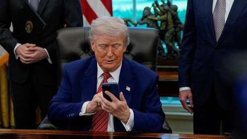 U.S. President Donald Trump holds an iPhone after it rang while he was speaking on the day he signs an executive order at the White House in Washington, D.C., U.S., May 23, 2025. REUTERS/Kent Nishimura