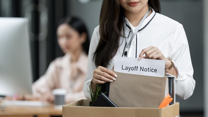 Closeup woman holding brown paper envelope in a Cardboard box standing in office.
