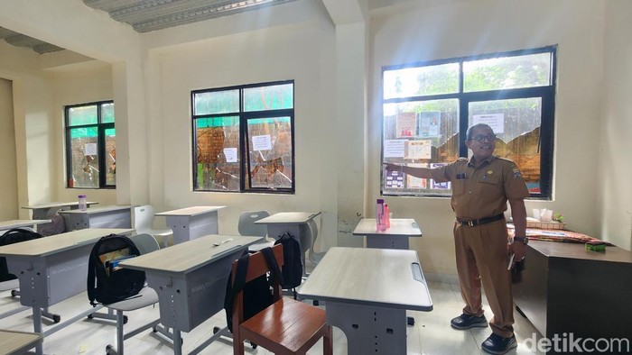 Kepsek SMPN 46 Palembang menunjukkan kaca sekolah yang dipecahkan.