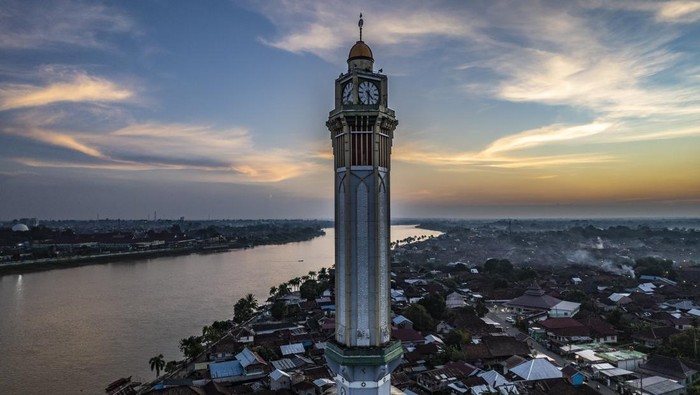 Menikmati Senja di Tepi Sungai Batanghari Jambi Berlatar Menara Gentala Arasy Foto udara suasana senja di perkampungan Seberang Kota Jambi dengan latar Menara Gentala Arasy di tepi Sungai Batanghari, Jambi, Minggu (25/5/2025). Pemerintah Provinsi Jambi sejak 10 tahun terakhir terus mengupayakan penumbuhan titik-titik ekonomi kreatif baru di dua sisi Sungai Batanghari, utamanya di wilayah Pasar Jambi dan Seberang Kota Jambi, melalui pembangunan Taman Menara Gentala Arasy dan Taman Putri Pinang Masak dengan anggaran mencapai Rp120 miliar lebih. ANTARA FOTO/Wahdi Septiawan