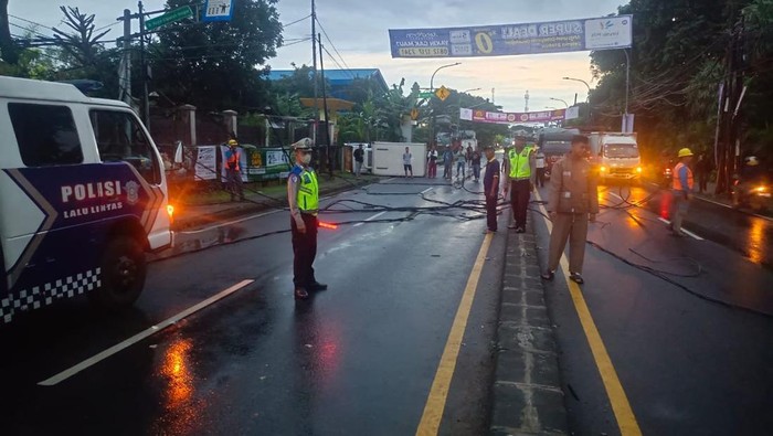 Mobil boks terguling usai tabrak tiang hingga bikin kabel serawut dan macet Jalan Raya Sawangan, Depok.