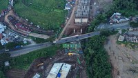 Sejumlah alat berat terlihat beroperasi di area proyek, sementara jalur jalan tol yang sedang dikerjakan tampak mulai terbentuk dengan jelas dari udara. Aktivitas para pekerja juga tampak intens, menandakan upaya percepatan penyelesaian proyek demi memenuhi target yang telah ditetapkan.
