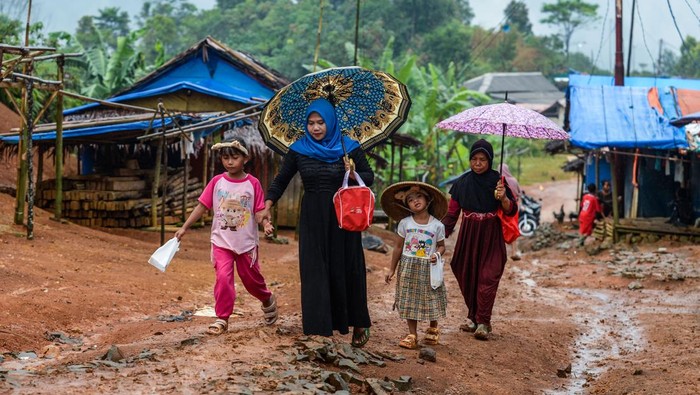 Sejumlah warga penyintas bencana banjir bandang dan longsor berjalan di sekitar hunian sementara (huntara) di Kampung Cigobang, Lebak, Banten, Senin (26/5/2025). Sebanyak 241 kepala keluarga (KK) yang merupakan korban bencana banjir bandang dan longsor pada tahun 2020 tersebut selama lima tahun masih bertahan di tenda huntara dengan akses yang sulit dijangkau dan mengharapkan pemerintah agar segera membangun hunian tetap (huntap) yang telah dijanjikan. ANTARA FOTO/Muhammad Bagus Khoirunas/Spt.