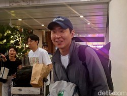 Lee Hyun Kyun bertopi biru tua dan jaket abu-abu terlihat membawa tas ransel berwarna hitam saat tiba di Bali.