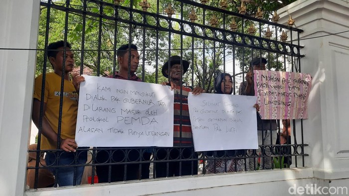 Massa petani memasang spanduk di pagar Pendopo Kabupaten Pati saat menyambut kedatangan Gubernur Jawa Tengah Ahmad Luthfi, Selasa (27/5/2025).