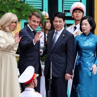 Kontras dengan insiden di pintu pesawat yang diwarnai ketegangan, Emmanuel Macron dan Brigitte terihat tersenyum bahagia. Foto: REUTERS/Chalinee Thirasupa