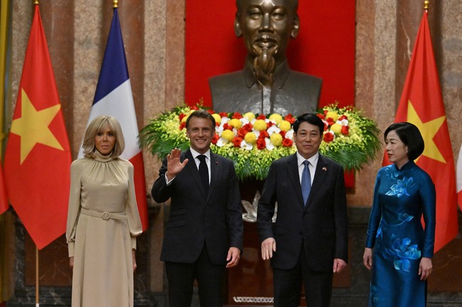 Dalam momen foto bersama Presiden Vietnam Luong Cong dan Ibu Negara Thi Minh Nguyet di Istana Kepresidenan, Macron terlihat melambaikan dan melempar senyum lebar. Di sampingnya, Brigitte yang mengenakan riasan wajah bernuansa nude menyunggingkan senyum tipis. Foto: Reuters