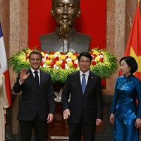 Dalam momen foto bersama Presiden Vietnam Luong Cong dan Ibu Negara Thi Minh Nguyet di Istana Kepresidenan, Macron terlihat melambaikan dan melempar senyum lebar. Di sampingnya, Brigitte yang mengenakan riasan wajah bernuansa nude menyunggingkan senyum tipis. Foto: Reuters