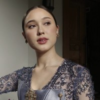 Atasan kebaya berbentuk korset berwarna lilac keperakan itu dilapisi dengan brokat berpayet halus dan memperlihatkan detail bordir floral dramatis di sepanjang lengan panjang transparan. Potongan sweetheart neckline yang berpadu dengan detail V-neck dalam aksen renda menghadirkan kesan feminin yang tetap berwibawa. Foto: dok. Instagram @yasminnapper