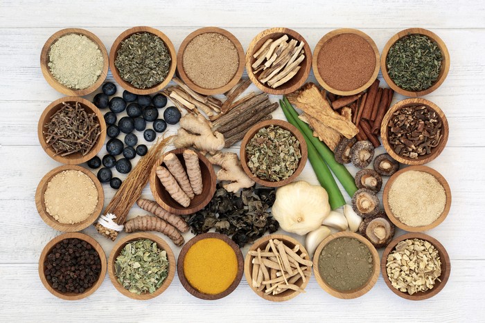 Adaptogen health food with herbs, spices, fruit & supplement powders. Natural plant based foods that help the body deal with stress & promote or restore normal physiological functions. On rustic wood.