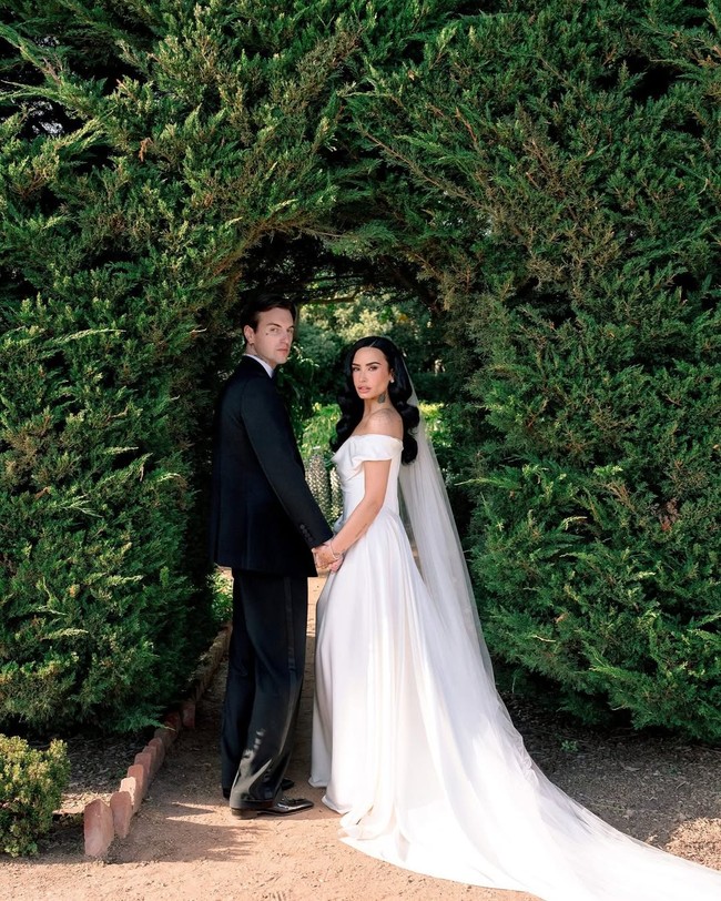 Pelantun lagu ‘Cool for the Summer’ ini tampil memukau dalam balutan gaun off-the-shoulder rancangan Vivienne Westwood, desainer asal Inggris yang dikenal dengan estetika dramatis dan siluet penuh statement. Foto: Instagram/@ddlovato @vogueweddings @josevilla