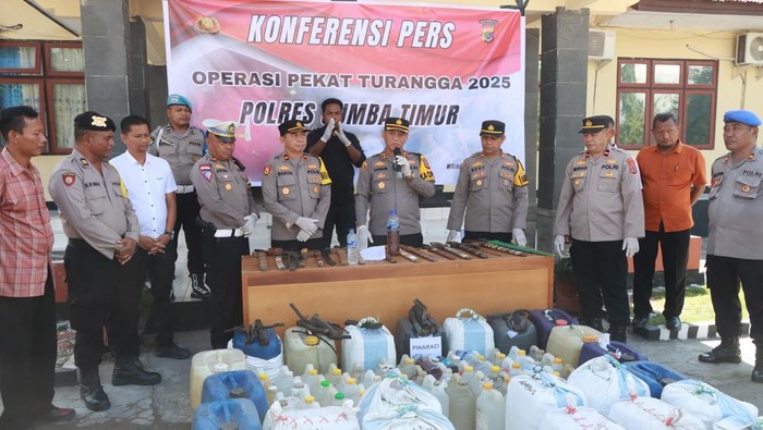 Kapolres Sumba Timur AKBP Gede Harimbawa memperlihatkan ribuan liter miras dalam jeriken dan belasan sajam hasil Operasi Pekat Turangga, Rabu (28/5/2025). (Dok. Humas Polres Sumba Timur)