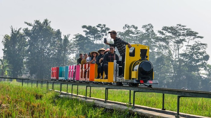 Pengunjung menaiki kereta di Desa Wisata Kiangroke, Banjaran, Kabupaten Bandung, Jawa Barat, Kamis (29/5/2025). Warga bekerja sama dengan pemerintah Desa Kiangroke, Kecamatan Banjaran untuk membuat wahana kereta api di tengah ladang persawahan yang ditujukan sebagai salah satu langkah menciptakan lapangan pekerjaan bagi warga sekitar dan meningkatkan kunjungan wisatawan serta memberikan alternatif wisata bagi masyarakat dengan tarif Rp15.000 satu putaran. ANTARA FOTO/Raisan Al Farisi/rwa.
