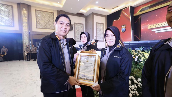 Kabidhumas POlda Jatim Kombes Jules Abraham Abast menyerahkan penghargaan kepada Kasi Humas Polres Probolinggo, Iptu Merdhania Pravita Shanty di acara Rakernis Humas Polda Jatim Tahun Anggaran 2025
