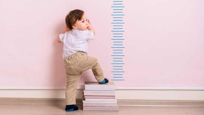Child measuring his height on wall. He is growing up so fast.